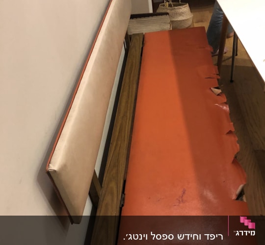 ריפוד כתום קרוע על ספסל עץ
